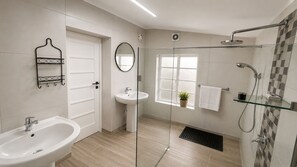 Ein modernes Badezimmer mit einer Duschkabine aus Glas, einem Waschbecken und einem Spiegel.