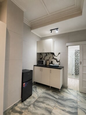 A compact kitchen with a refrigerator, microwave, and cabinets. - 95 on Queen Guest & Lodge – Peaceful Stay in a Great Location (Johannesburg)