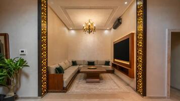 A modern living room with a sectional sofa, a coffee table, a flat-screen TV, and a decorative wall panel.