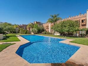 A rectangular swimming pool with a clear blue water surface, surrounded by a paved walkway, and adjacent to a building with a castle-like architectural style. - Villa Assi Prestige · 2 Private Hot Tubs, Breakfast & Airport Transfers (Marrakech)