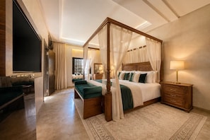 Ein Bett mit Baldachin, ein an der Wand montierter Fernseher und ein Nachttisch aus Holz mit einer Lampe.