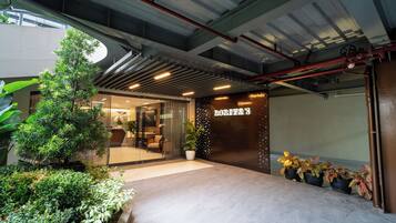 Una entrada moderna de edificio con puerta de vidrio, plantas en macetas y un letrero que dice 'HOTEL'.