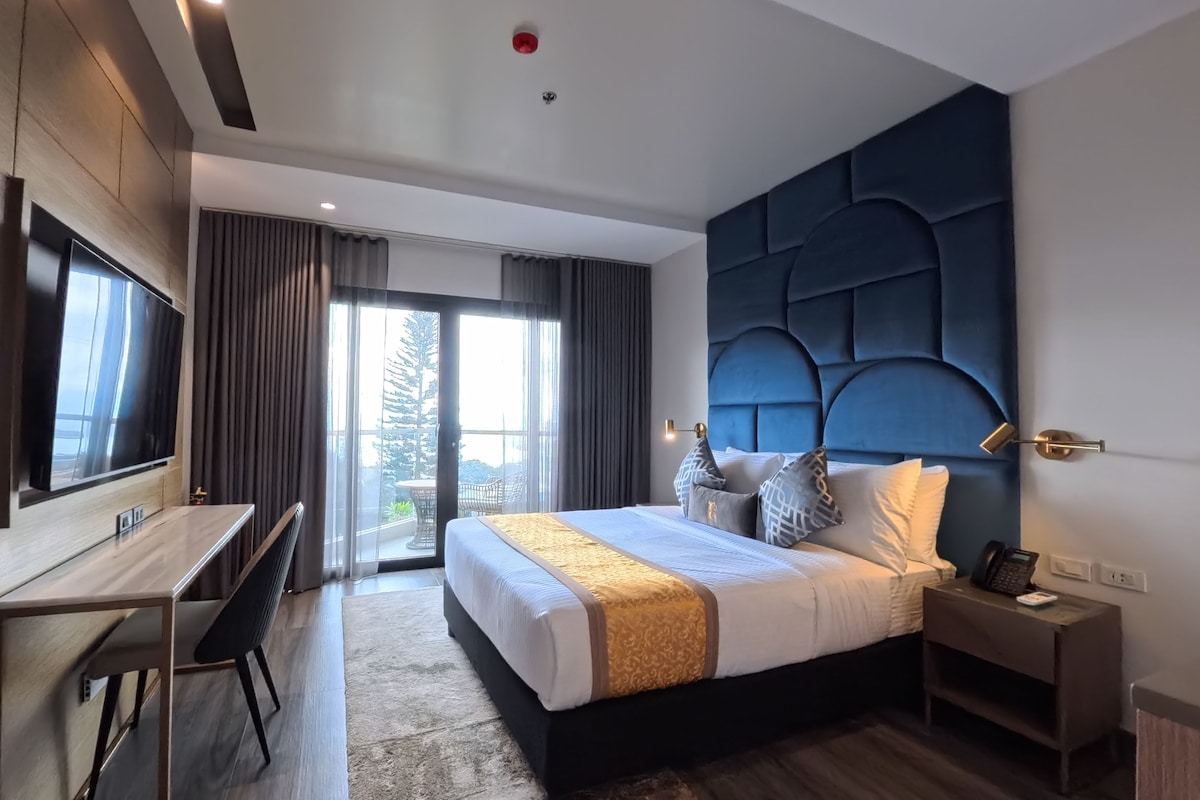 Et moderne hotelværelse med seng, skrivebord og fjernsyn.