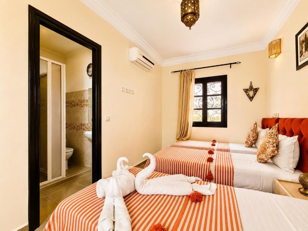 A hotel room with two beds, a bathroom, and a window with curtains.