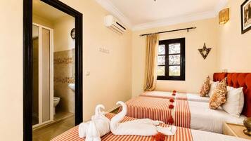 A hotel room with two beds, a bathroom, and a window with curtains.