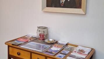 A wooden console table with a framed painting above it, a small vase, and a potted plant.