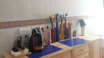 A kitchen counter with a clock, a coffee maker, and various kitchen utensils.