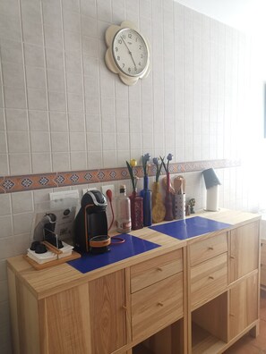 A kitchen counter with a clock, a coffee maker, and various kitchen utensils.