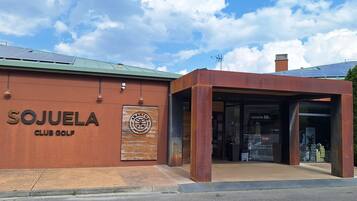 A building with a sign reading 'SOJUELA CLUB GOLF' and a logo for 'BANTOS RESTAURANT'.