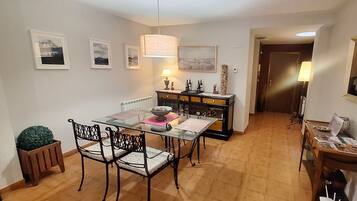 A dining area with a glass table, black chairs, a wooden cabinet, and framed pictures on the walls.