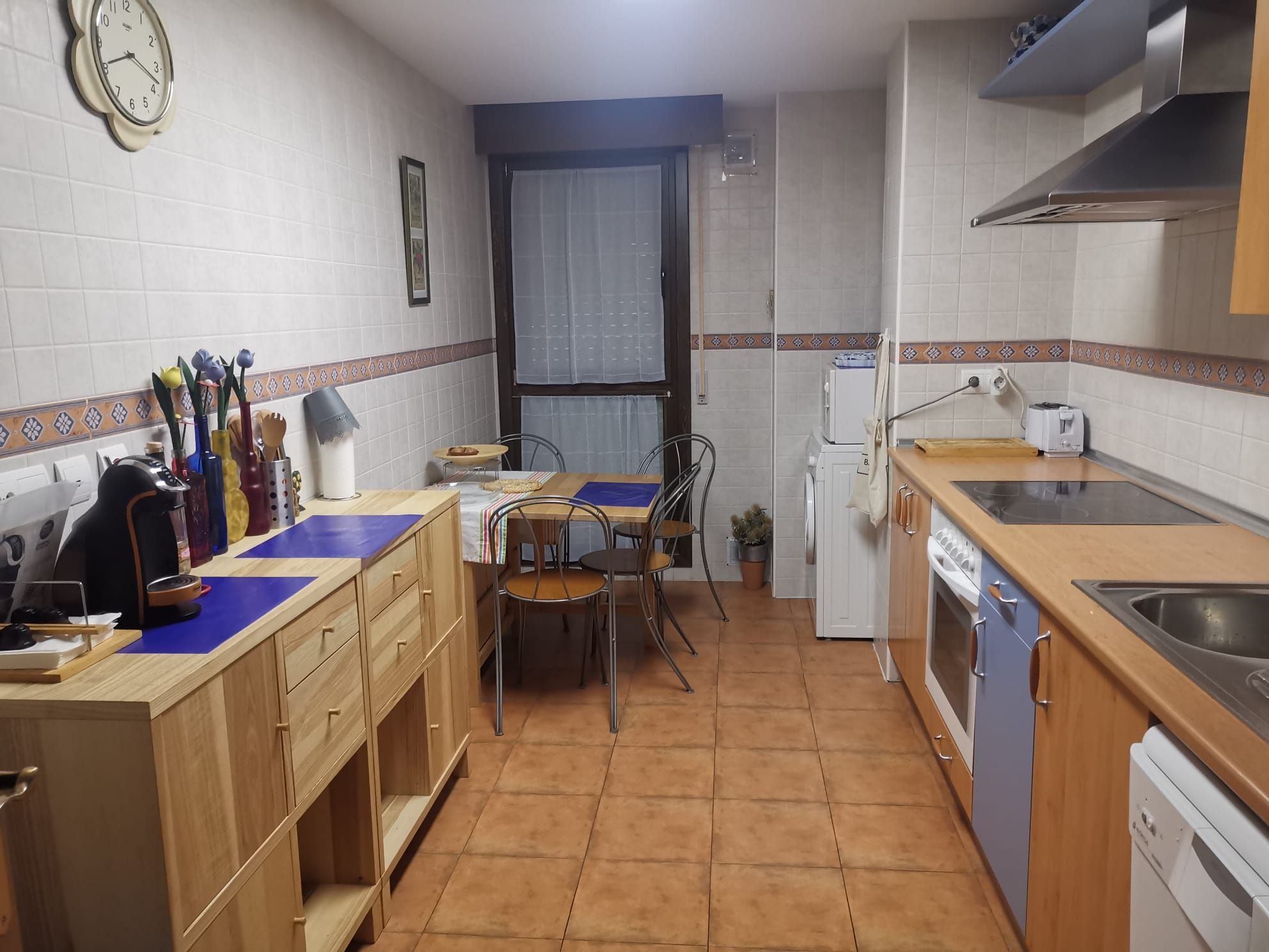 A compact kitchen with a dining table, chairs, a refrigerator, and a dishwasher.
