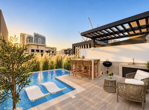A rooftop pool area with lounge chairs, a bar, and a pergola. - Pool Days. City Nights. Your Private VILLA Escape (دبي)