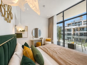 Ein modernes Hotelzimmer mit einem großen Bett, einem Schreibtisch, einem Sessel und einem Balkon mit Stadtblick.