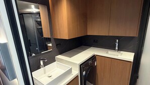 Une cuisine moderne avec des meubles en bois, un lave-vaisselle encastré et un plan de travail blanc.