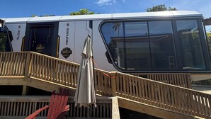 Une terrasse avec une chaise rouge et une petite table, donnant sur un bateau blanc portant l’inscription « LIONHEART ».