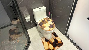 Une salle de bain comprenant des toilettes, une douche et un espace douche délimité par des parois en verre.