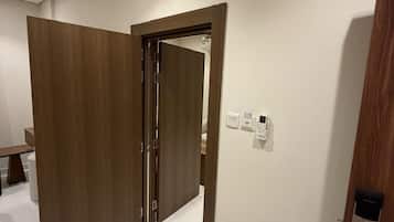 A hallway with a wooden door, a white wall, and a doorbell.