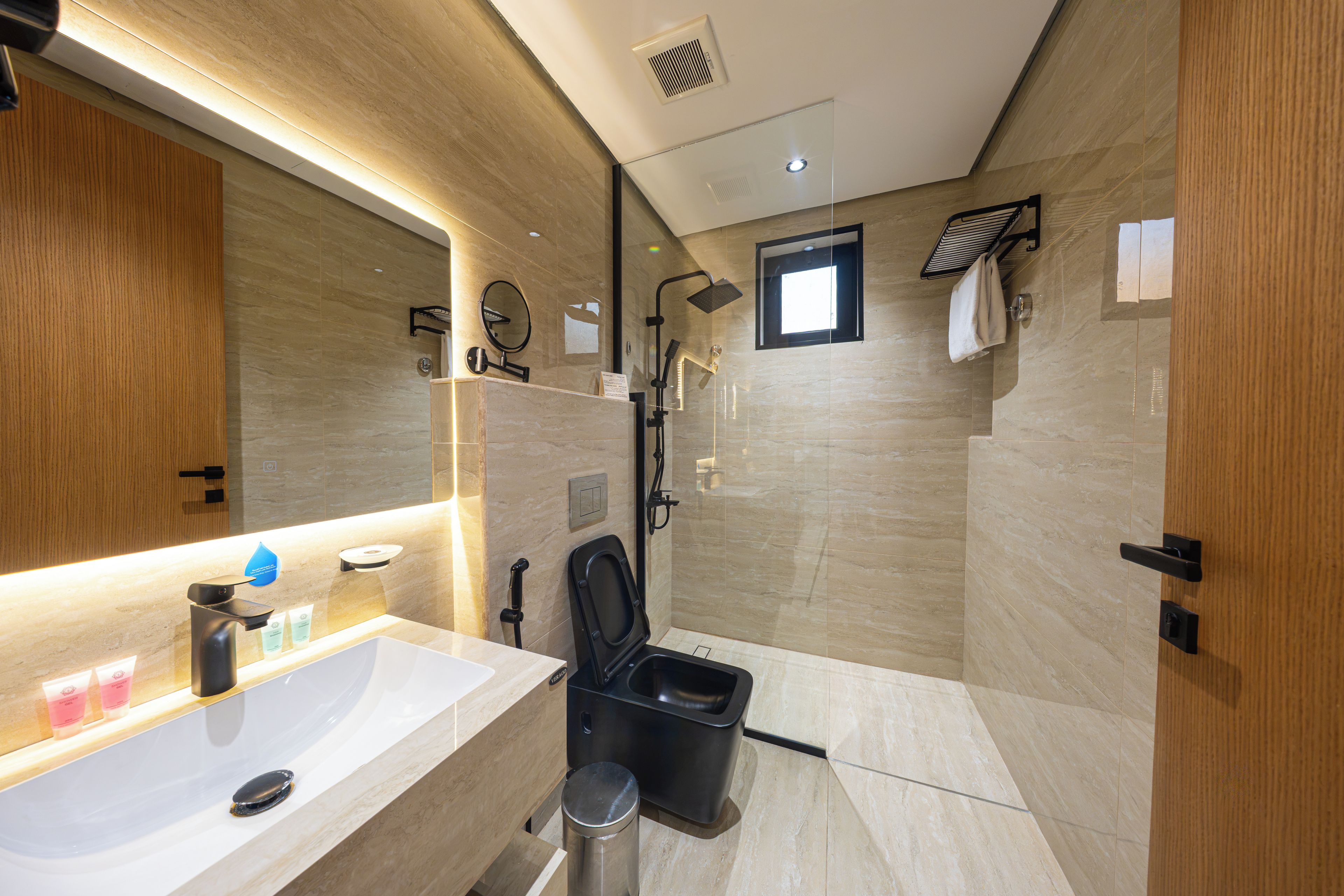 Een moderne badkamer met een grote spiegel, een wastafel, toilet en douche.