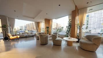 A spacious lobby with modern furniture, large windows, and a view of the cityscape.