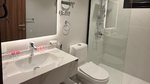 Ein modernes Badezimmer mit großem Spiegel, Waschbecken, Toilette und einer Duschkabine.