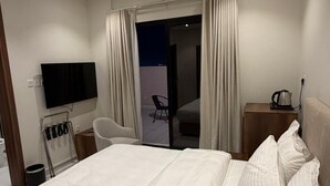 Ein Hotelzimmer mit Bett, Fernseher, Sessel, Schreibtisch und Blick nach draußen.