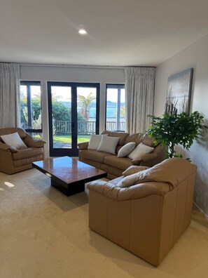Una sala de estar moderna con un conjunto de sofás, una mesa de centro y un amplio ventanal con vistas al exterior.