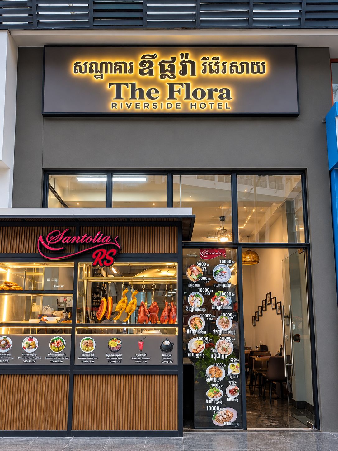 A hotel entrance with a sign for 'The Flora Riverside Hotel' and a food counter named 'Santolia RS' displaying various dishes.