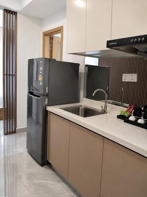 Una cocina moderna con refrigerador empotrado, pileta de acero inoxidable y extractor.