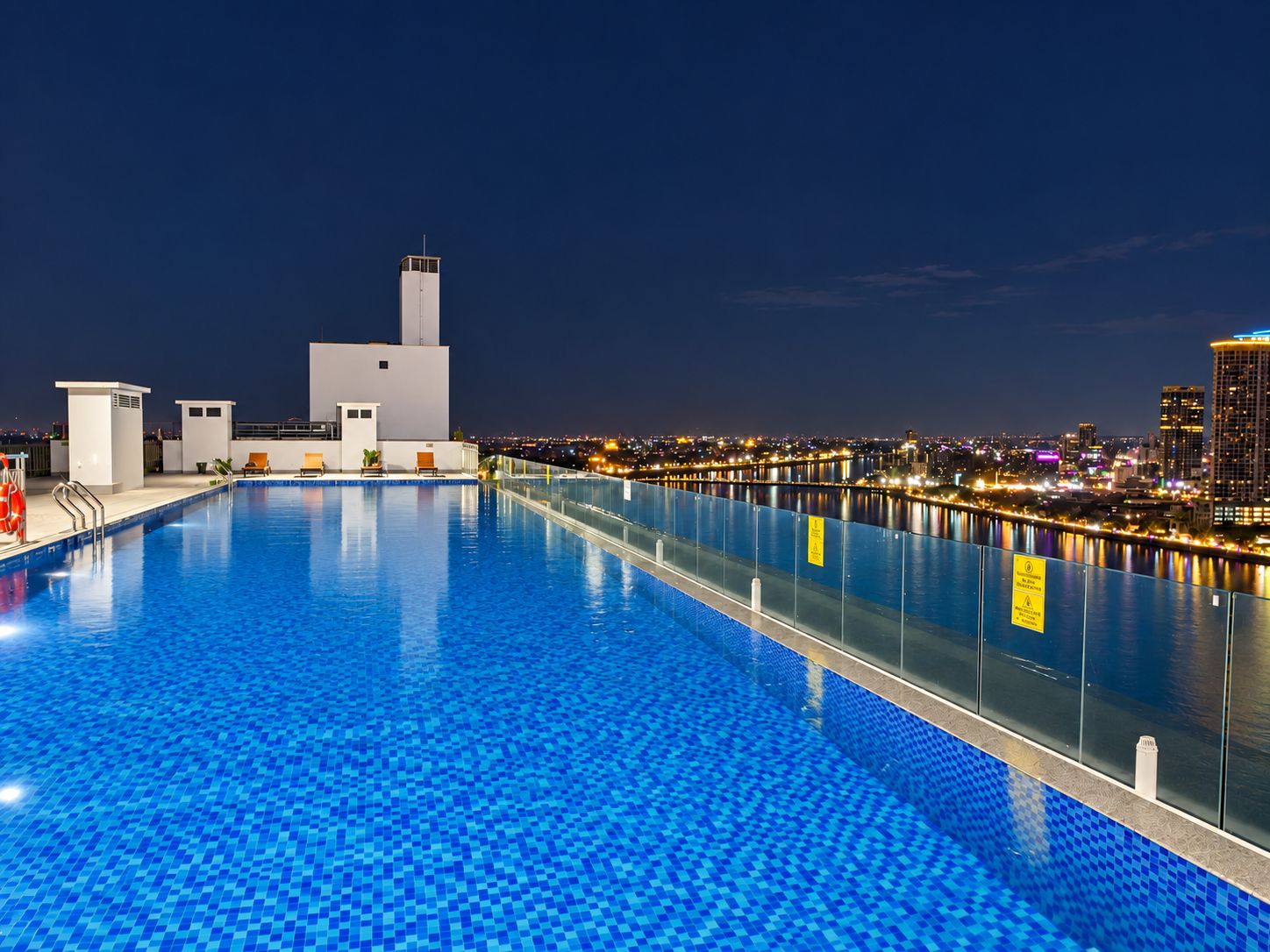 A swimming pool with a cityscape view at night.