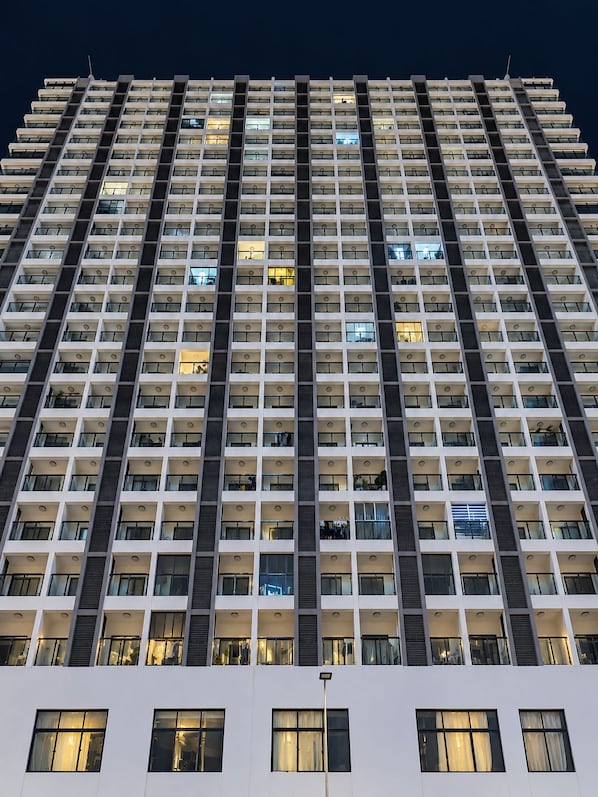 Un edificio alto con varios pisos, que presenta una cuadrícula uniforme de ventanas y balcones.
