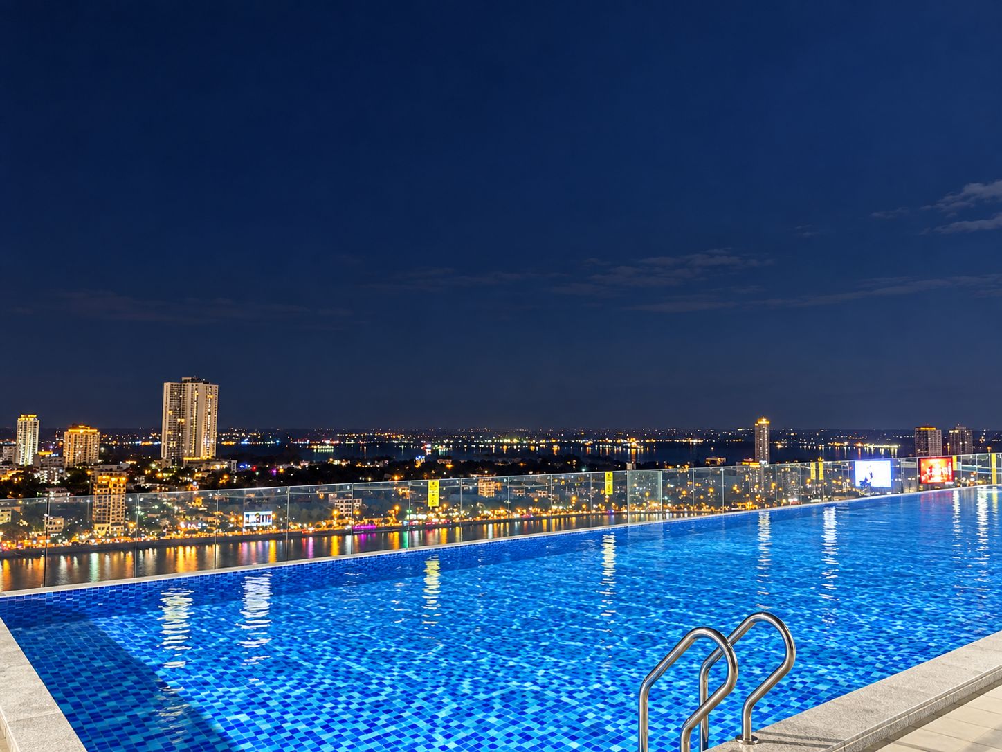 A swimming pool with a cityscape view at night.