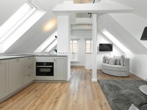 A modern loft with a kitchen, dining area, and living space, featuring skylights and a flat-screen TV. - 272 - Apartment Lighthouse (Juist)