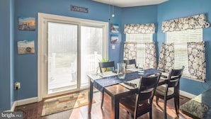 A dining area with a table, chairs, and a view through a sliding glass door. - Private 5BR Estate with Hot Tub, Pool & Movie Room (Hughesville)