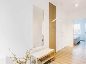 Un interior moderno con un banco de madera, un espejo y una puerta que da a otra habitación.