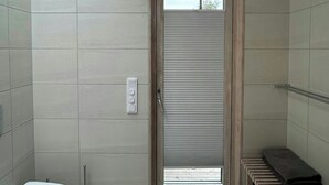 Une salle de bain moderne équipée de toilettes, d’un bidet et d’un espace douche.