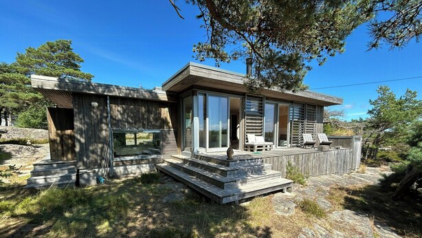 Une maison moderne dotée d’une terrasse, de grandes fenêtres et d’un chemin en pierre.