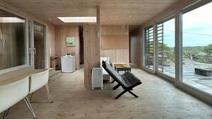 Une pièce spacieuse avec une grande fenêtre, un radiateur, un canapé et un plancher en bois.
