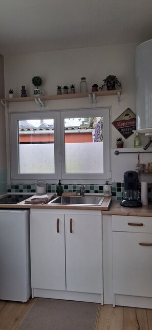 Eine Küche mit einem Doppelwaschbecken, einer Kaffeemaschine und einem Fenster mit Blick auf ein Gebäude.