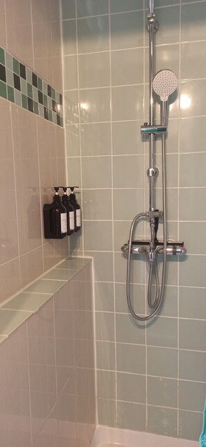 Ein Badezimmer mit Dusche, Seifenspender und einer Shampoo-Flasche.