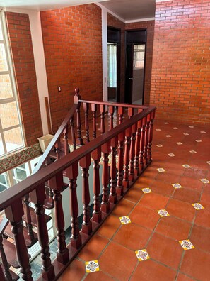 Eine Treppe mit hölzernen Geländern führt zu einem Zwischenpodest mit einer Glastür.