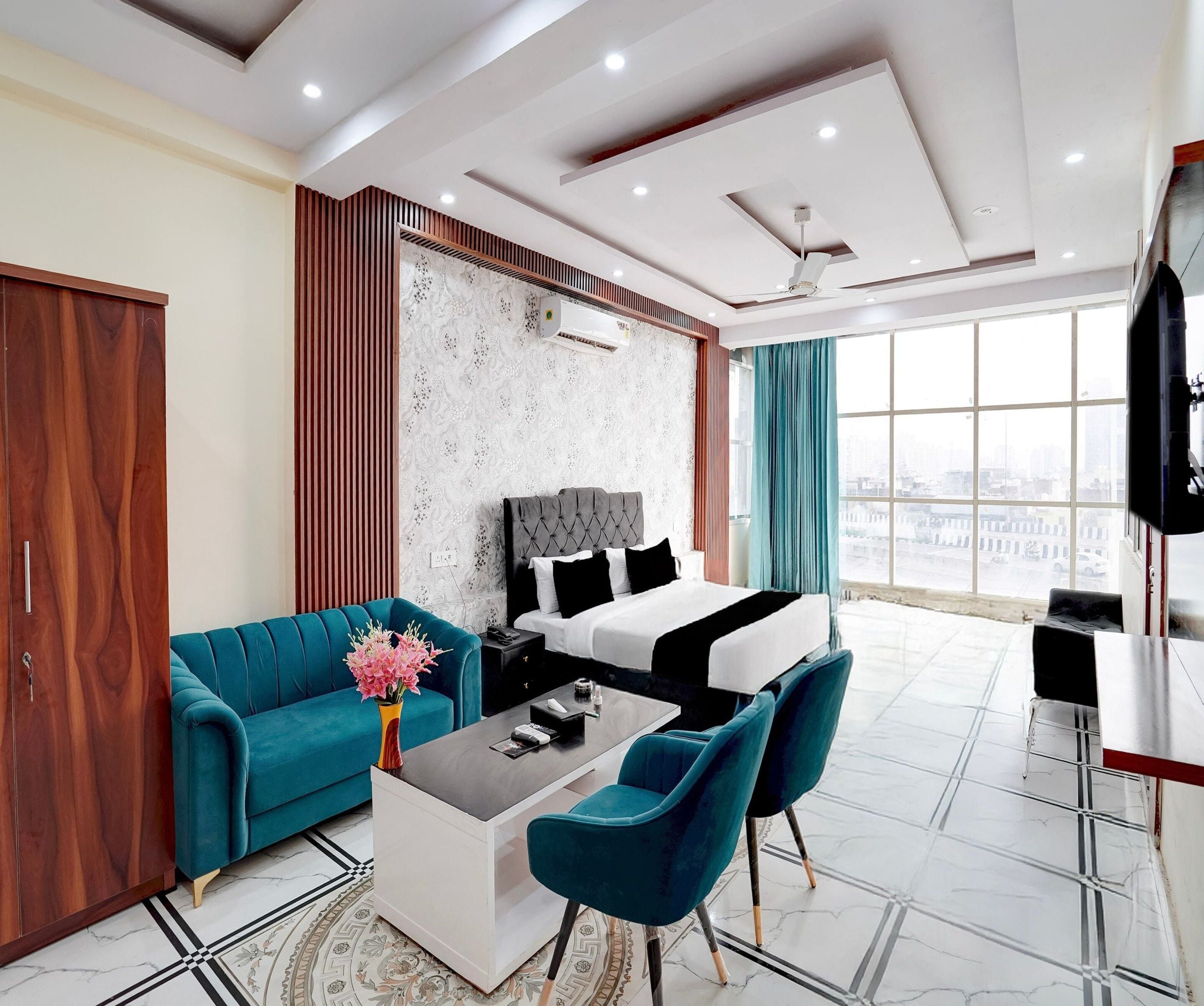 Une chambre d’hôtel moderne avec un grand lit, un canapé, une table basse et un téléviseur.