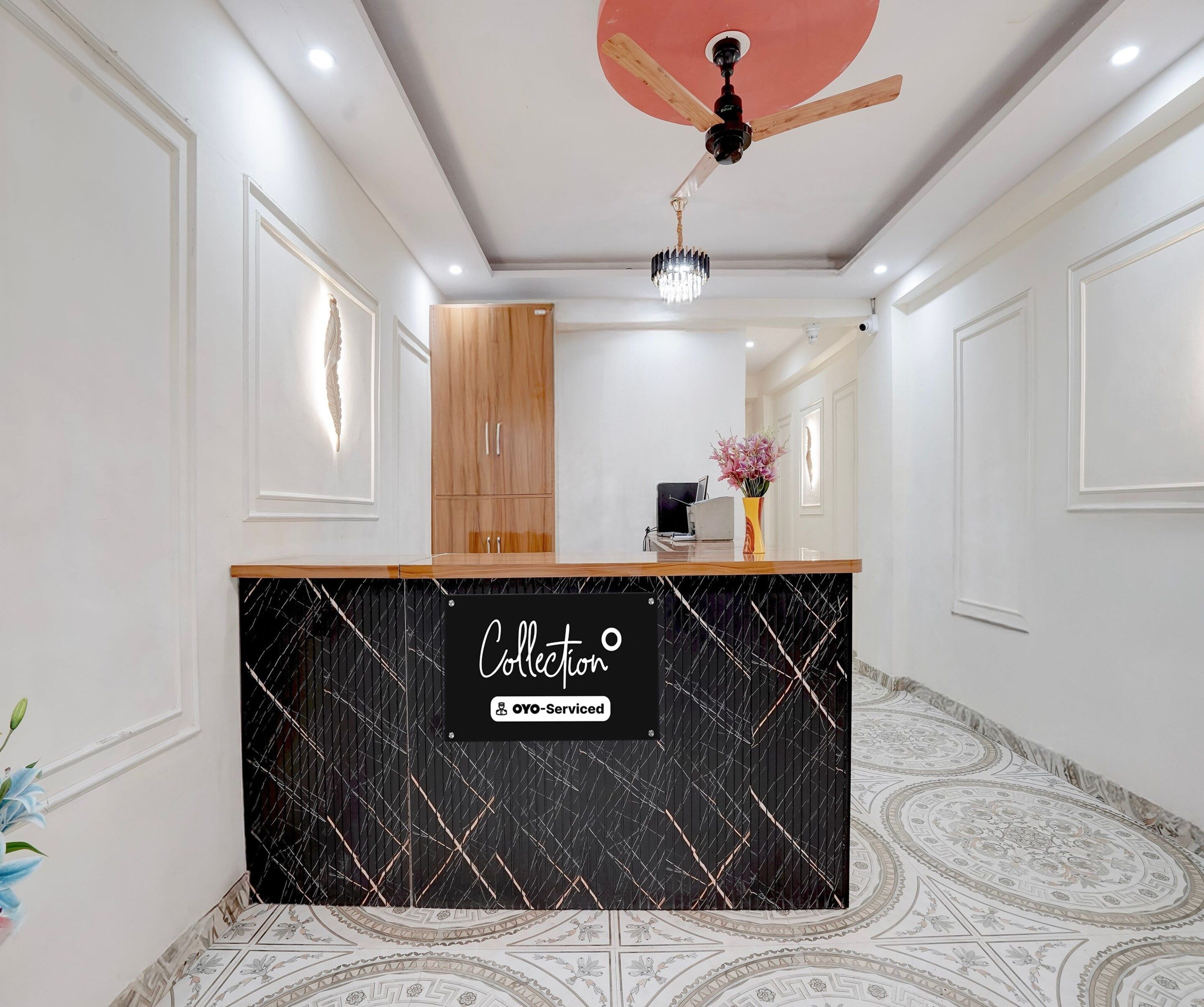 A reception area with a black marble counter, wooden cabinets, and a ceiling fan.