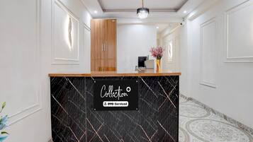 A reception area with a black marble counter, wooden cabinets, and a ceiling fan.