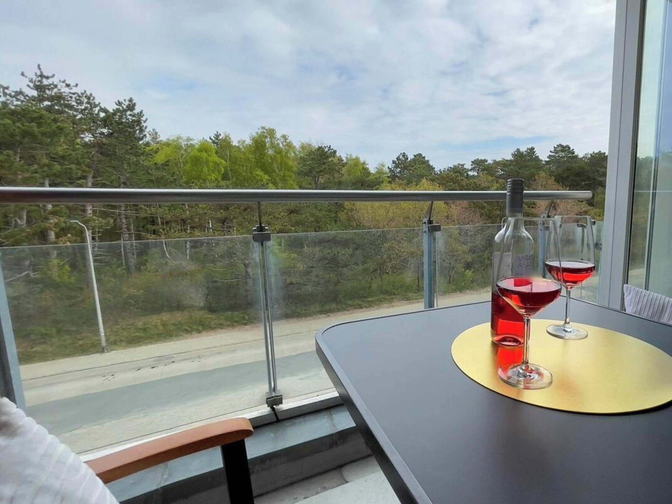 A balcony with a table, two wine glasses, and a bottle of wine.