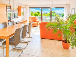 A modern living room with a dining area, large windows, and a potted plant. - Albatros Royal by Interhome (Tossens)