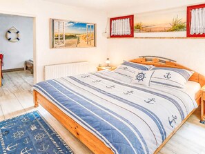 A bedroom with a bed, a nightstand, a lamp, a window with a view, and a door. - Albatros Royal by Interhome (Tossens)