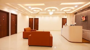 A reception area with a curved reception desk, two sofas, and a chandelier. - S V GRAND INN (Bengaluru)