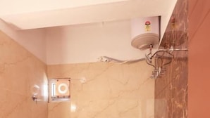 A bathroom with a toilet, shower, and a bucket. - S V GRAND INN (Bengaluru)