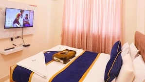 A hotel room with a bed, a television, and a ceiling fan. - S V GRAND INN (Bengaluru)