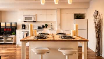 Une cuisine moderne avec une table à manger pour quatre personnes, un téléviseur diffusant du contenu « NETFLIX » et un four à micro-ondes.